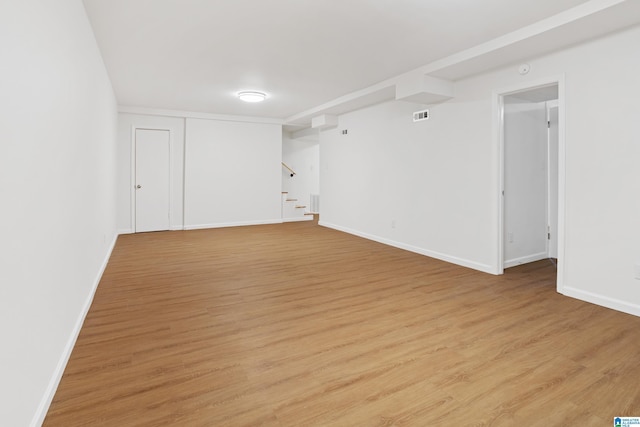 spare room with light wood-style floors, stairway, and baseboards