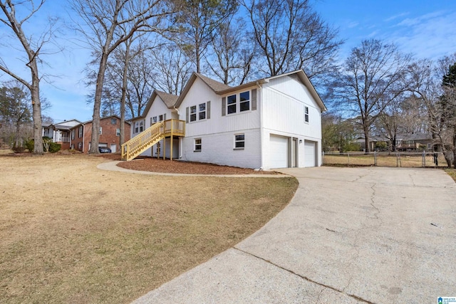 view of front of home featuring driveway, a garage, stairway, fence, and brick siding