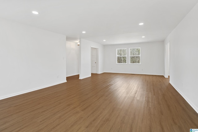 empty room with baseboards, wood finished floors, and recessed lighting