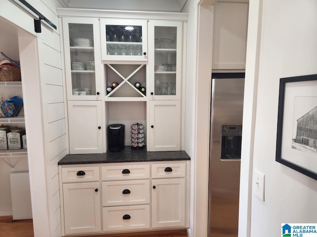 bar featuring stainless steel fridge with ice dispenser