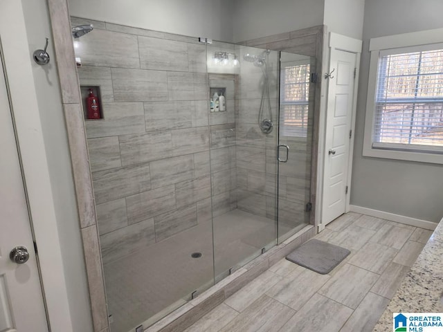 full bathroom featuring wood finish floors, a shower stall, and baseboards