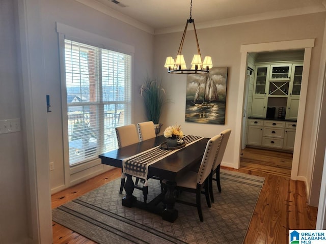 dining room with an inviting chandelier, wood finished floors, visible vents, and crown molding