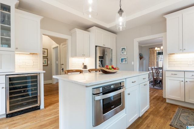 kitchen featuring light wood-style flooring, beverage cooler, stainless steel appliances, white cabinets, and light countertops