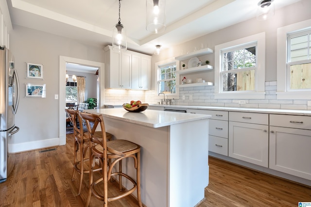 kitchen with backsplash, a center island, dark wood-type flooring, stainless steel fridge with ice dispenser, and light countertops