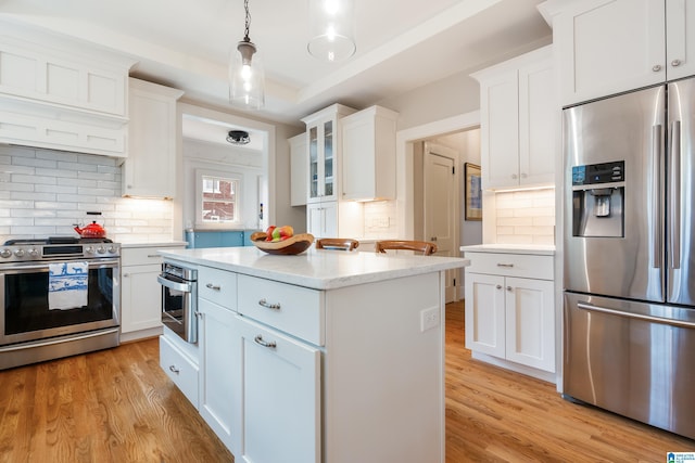 kitchen with white cabinetry, a kitchen island, appliances with stainless steel finishes, and light wood finished floors