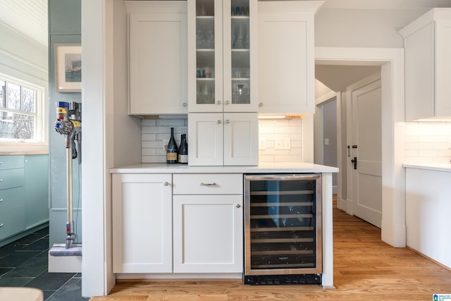 bar featuring beverage cooler, backsplash, a dry bar, and light wood-style flooring