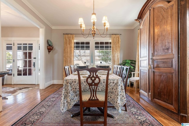 dining room featuring crown molding, light wood-style floors, baseboards, and a chandelier