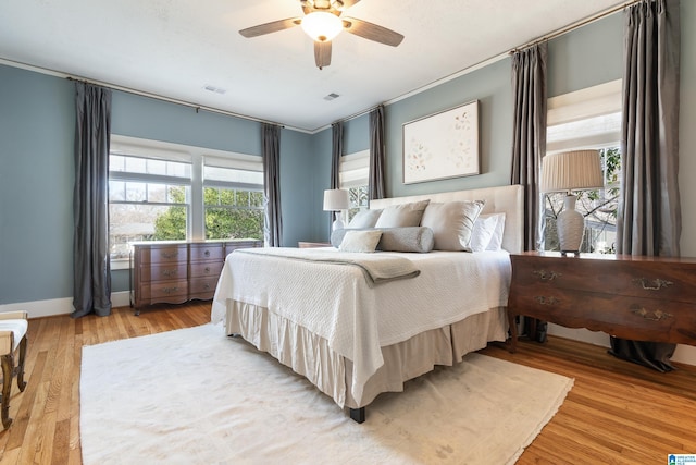 bedroom with visible vents, baseboards, light wood-style floors, and ceiling fan