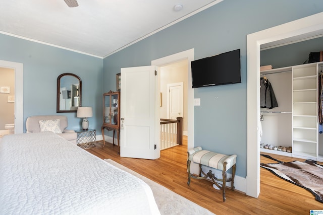 bedroom featuring a closet, baseboards, light wood-style flooring, and crown molding