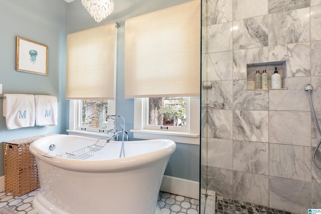 bathroom featuring a soaking tub, baseboards, and a tile shower