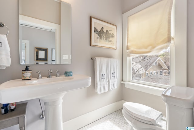 bathroom with tile patterned floors, toilet, baseboards, and a sink