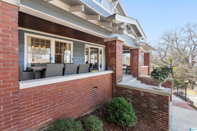 view of exterior entry with brick siding and covered porch