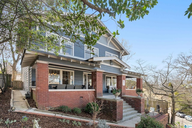 view of front of home with brick siding, a porch, and fence