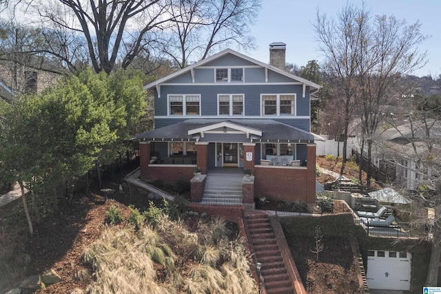 american foursquare style home with fence, a porch, a chimney, stairs, and brick siding