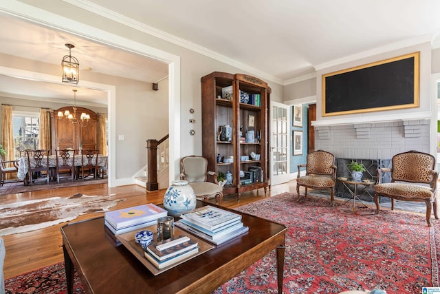 living area featuring wood finished floors, an inviting chandelier, crown molding, baseboards, and stairs