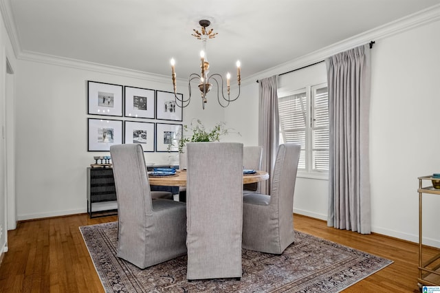 dining room featuring baseboards, wood finished floors, a chandelier, and crown molding