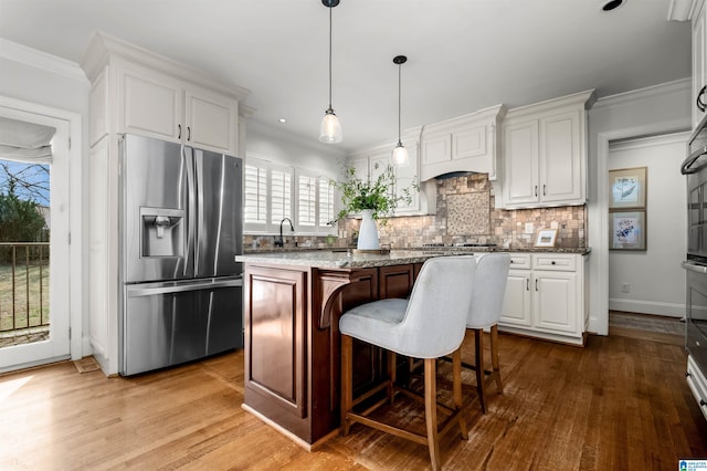 kitchen with tasteful backsplash, appliances with stainless steel finishes, white cabinets, and crown molding