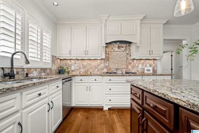 kitchen featuring ornamental molding, decorative backsplash, stainless steel appliances, a sink, and white cabinetry