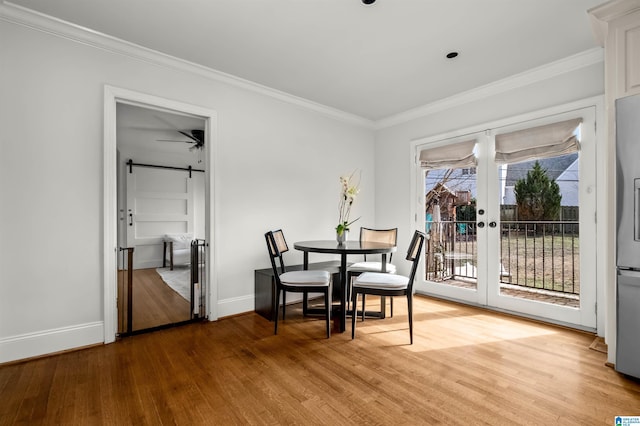 unfurnished dining area with a barn door, crown molding, wood finished floors, and french doors