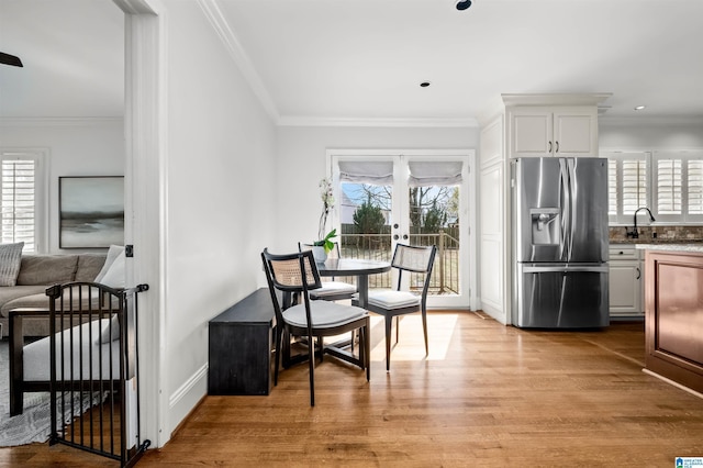 dining space featuring a wealth of natural light, light wood-type flooring, ornamental molding, and french doors