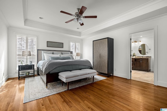 bedroom with a tray ceiling, baseboards, and light wood finished floors