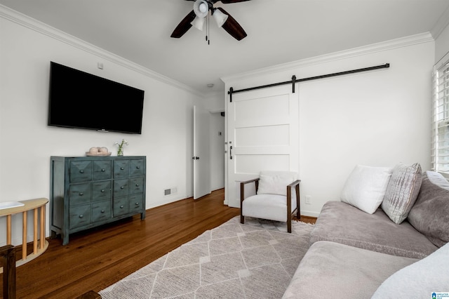 living area featuring visible vents, ornamental molding, a ceiling fan, wood finished floors, and a barn door