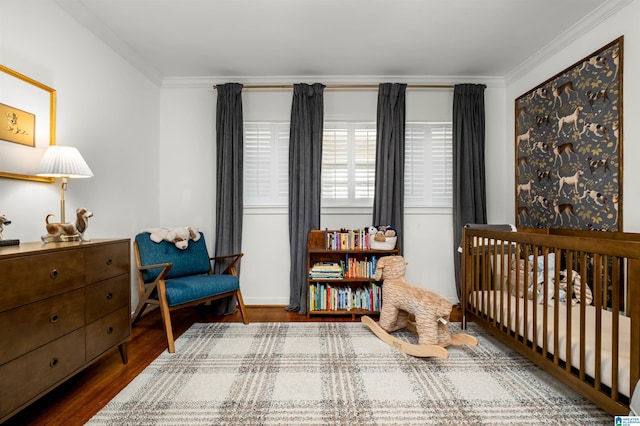 bedroom featuring crown molding, a nursery area, and wood finished floors