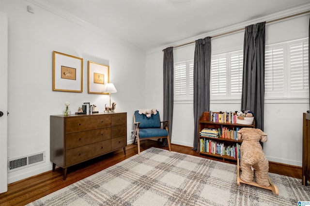 living area featuring visible vents, baseboards, and wood finished floors