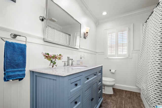 bathroom featuring vanity, wood finished floors, wainscoting, crown molding, and toilet