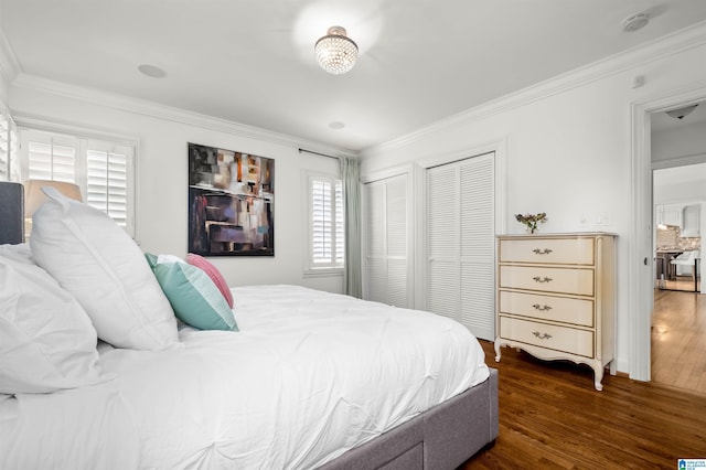 bedroom with two closets, ornamental molding, and dark wood-style flooring