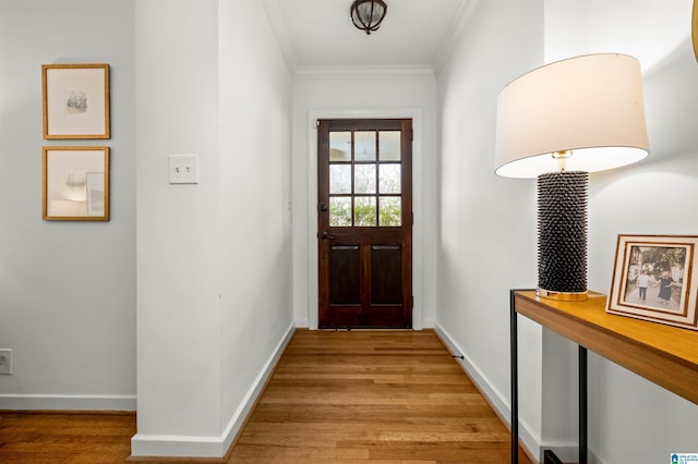 doorway to outside featuring baseboards, light wood-style floors, and ornamental molding