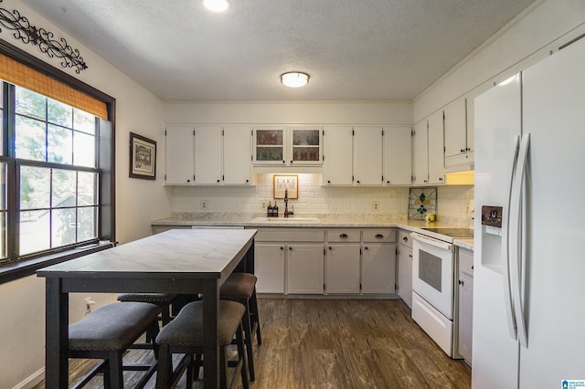 kitchen featuring dark wood finished floors, tasteful backsplash, a sink, a textured ceiling, and white appliances