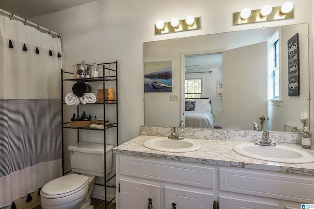 full bath with double vanity, a sink, toilet, and ensuite bathroom