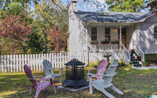 view of yard featuring covered porch, a fire pit, and fence