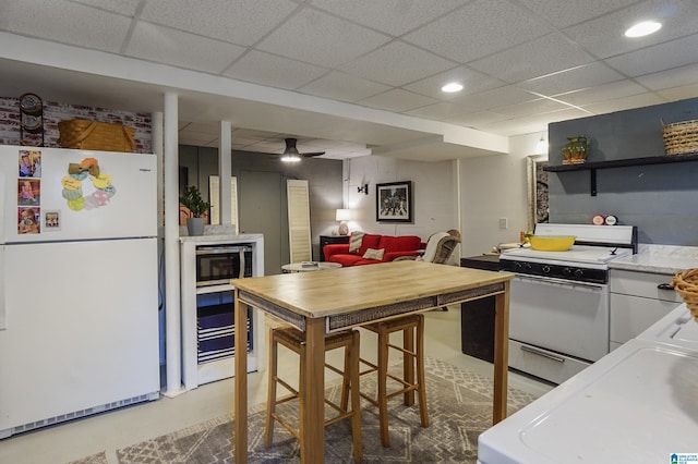 kitchen featuring a paneled ceiling, recessed lighting, white appliances, light countertops, and open shelves