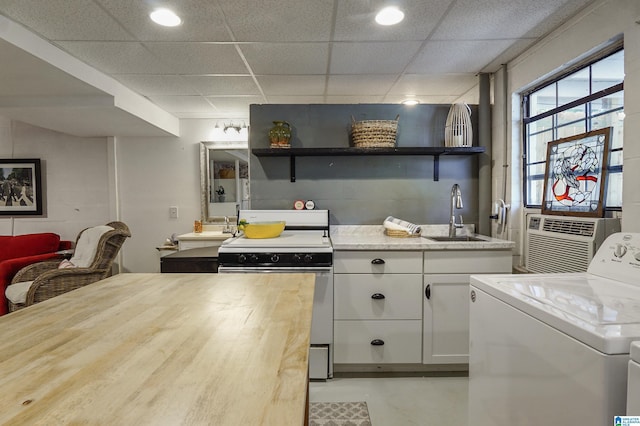 kitchen featuring finished concrete flooring, washer / dryer, electric range, open shelves, and a sink