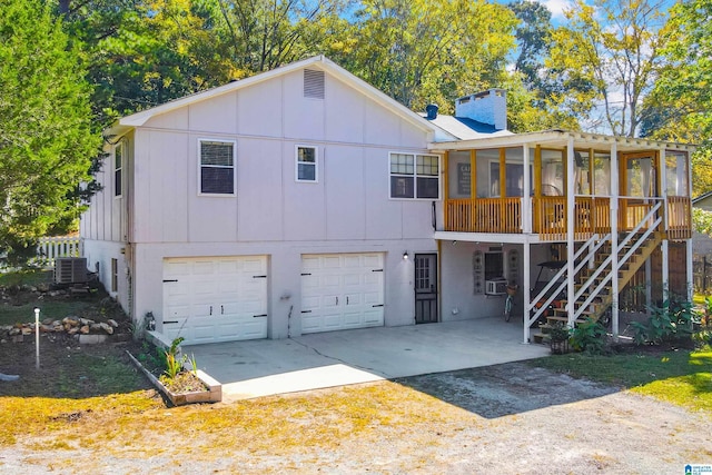 view of front of property featuring a chimney, an attached garage, a sunroom, cooling unit, and stairs