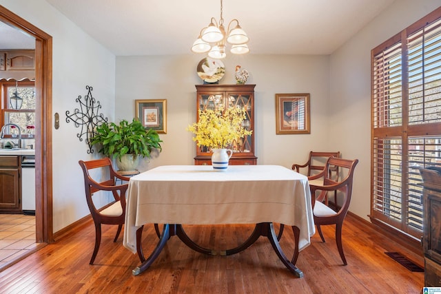 dining room featuring a notable chandelier, light wood-style flooring, visible vents, and a healthy amount of sunlight