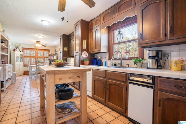 kitchen featuring ceiling fan, plenty of natural light, a sink, and tile counters