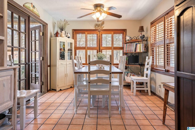 dining space featuring a ceiling fan, a textured ceiling, baseboards, and light tile patterned floors