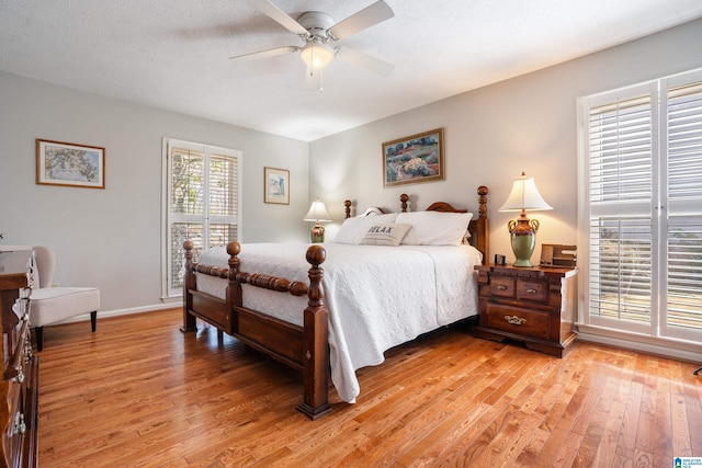 bedroom with light wood finished floors, a ceiling fan, baseboards, and a textured ceiling