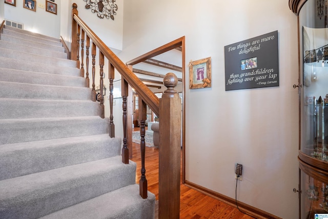 stairway with wood finished floors, visible vents, and baseboards