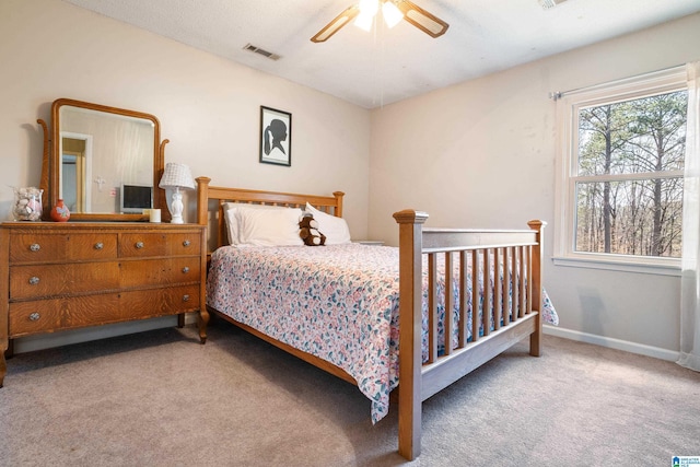 carpeted bedroom featuring a ceiling fan, visible vents, and baseboards