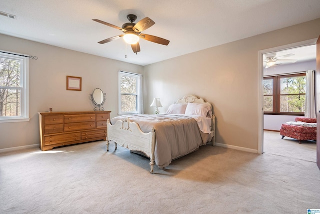 bedroom with light colored carpet, ceiling fan, visible vents, and baseboards