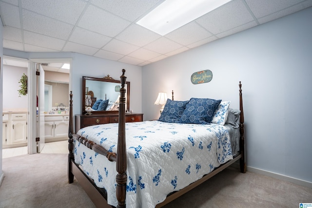 bedroom featuring ensuite bathroom, a drop ceiling, carpet, and baseboards