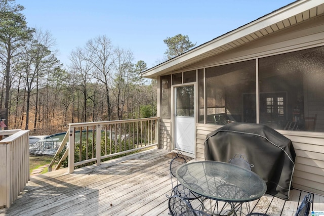 deck with outdoor dining space, a sunroom, and area for grilling