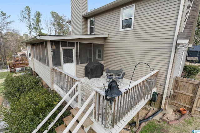 wooden terrace featuring a sunroom, a grill, and fence