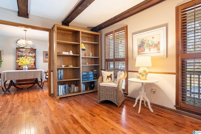 sitting room with beamed ceiling, hardwood / wood-style flooring, and a notable chandelier