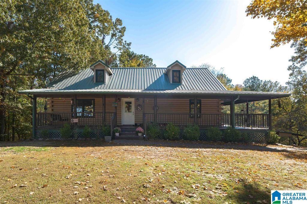 cabin featuring covered porch, metal roof, log exterior, and a front yard