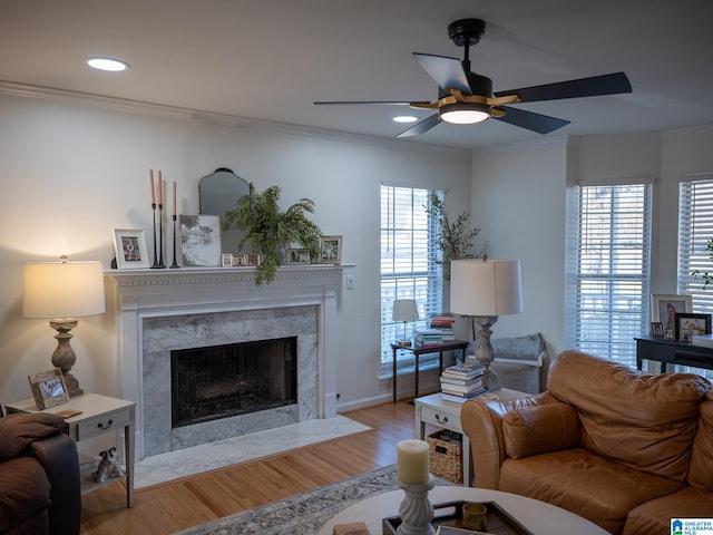 living room featuring a fireplace, recessed lighting, ornamental molding, a ceiling fan, and wood finished floors